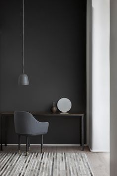 a gray chair sitting on top of a wooden table next to a white vase and lamp