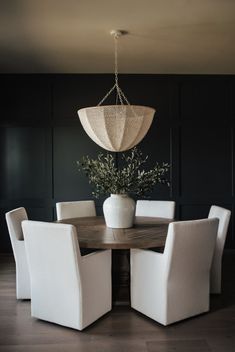 a dining room table with white chairs and a plant in the center on top of it