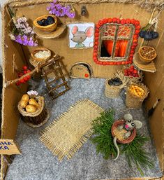 an open cardboard box filled with lots of food and decorations on top of carpeted flooring