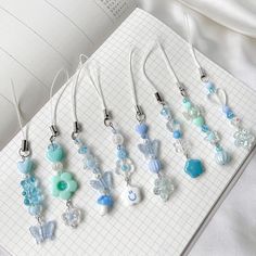 a bunch of necklaces sitting on top of a white book next to a pen