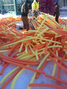 some people are looking at orange and yellow hoses on the ground in front of a building