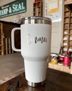 a white coffee cup sitting on top of a wooden table next to a store sign