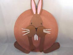 a paper plate shaped like a rabbit sitting on the ground with its eyes closed and ears wide open