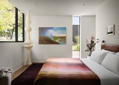 a bedroom with a large bed next to a painting on the wall and an open window