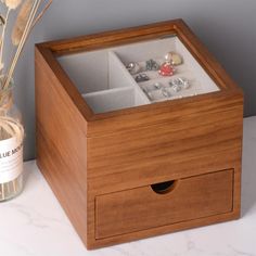 a wooden box with jewelry inside sitting on a table next to a vase filled with flowers