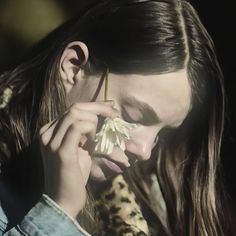 a woman with long hair holding a flower in her hand