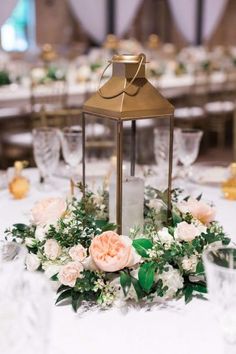 a lantern is on top of a table with flowers and greenery