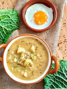 a bowl of soup with an egg on top and some lettuce next to it