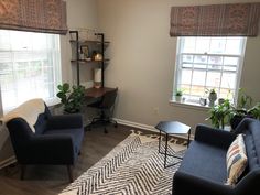 a living room with two blue chairs and a black table in front of the window