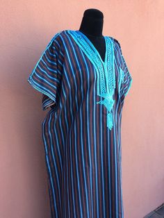 Stylish bohemian unisex vintage Moroccan kaftan/caftan, with lovely focal color that reminds me of that famous blue hue of Chefchaouen; predominantly 2 blues, also red & subtle green... all natural cotton, lightweight, great as a dress in mild to warm weather, or equally as at home lounge wear... with beautiful embroidery around the v-shaped neck & bust, & also surrounding the functional front pocket. With the hamsa or hand of Fatima talismanic symbol of protection at the solar plexu Bohemian Style Brown Long Thobe, Bohemian Style Long Brown Thobe, Brown Bohemian Long Thobe, Blue Embroidered Folk Kaftan, Bohemian Blue Thobe For Vacation, Blue Folk Style Kaftan For Festivals, Blue Embroidered Short Sleeve Kaftan, Bohemian Blue Long Thobe, Bohemian Long Blue Thobe