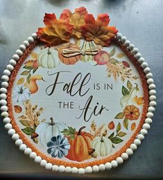 a decorative fall is in the air sign with pumpkins and leaves on it's side