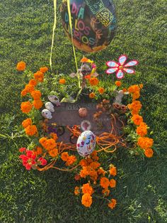 an arrangement of flowers and balloons on the ground in front of a headstone with skulls