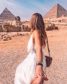 a man and woman holding hands in front of the pyramids