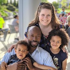 a woman and two children are smiling for the camera while standing in front of a group of people