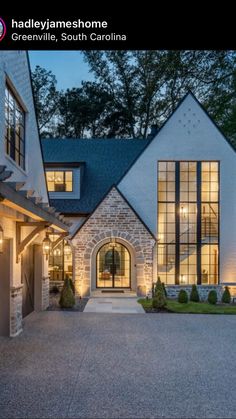 a large house with two garages and lights on the front door is lit up at night