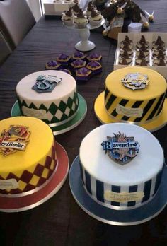 a table topped with lots of cakes covered in harry potter themed icing and cupcakes