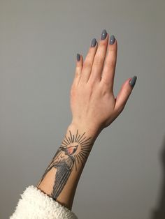 a woman's hand with a tattoo on her left arm and the sun above her head