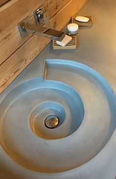 a bathroom sink that is made out of concrete and has a wooden wall behind it