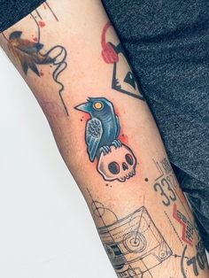 a man's arm with a skull and bird tattoo on the left side of his arm