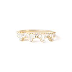 a yellow gold ring with five baguetts of diamonds on the side, set against a white background