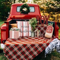 an old red truck with christmas presents in the bed and decorations on it's back