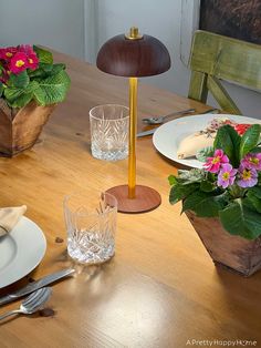 a wooden table topped with plates and vases filled with flowers on top of it