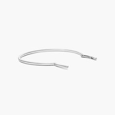 a thin silver bracelet on a white background