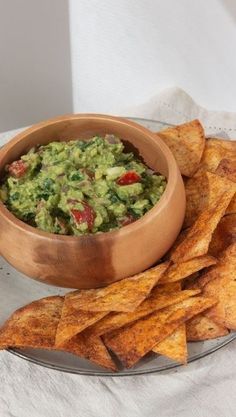 a wooden bowl filled with guacamole next to some tortilla chips