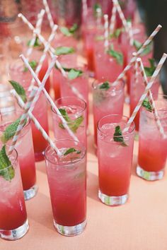 many glasses filled with different types of drinks on a table together and straws sticking out of them