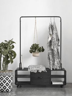 an iron rack with plants and towels hanging from it's sides, next to a potted plant