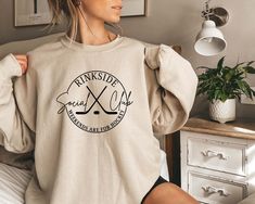 a woman sitting on top of a bed wearing a sweatshirt