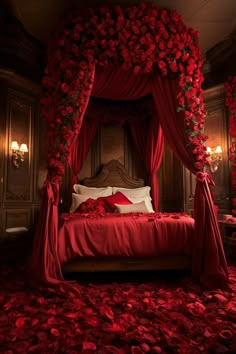 a bed covered in red roses and drapes with lights on either side of it