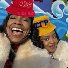 two women with hats on their heads posing for a photo in front of a graffiti wall