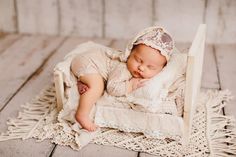 a newborn baby is sleeping on a white chair with a lace headband and bonnet