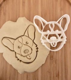 two cookie cutters sitting next to each other on a cutting board, one with a dog's head and the other with a cat's face