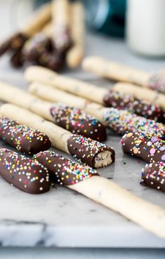 chocolate covered pretzels with sprinkles are on a tray next to some sticks