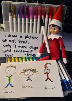 an elf with markers and crayons next to a sign that says i draw a picture of us