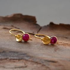 "These beautiful 24k gold vermeil earrings feature a genuine faceted ruby and a twisted textured small disc. Vermeil is a thick coat of 24 karat gold on solid sterling silver. The ruby stone, set in an open-back setting, is suspended from a French style ear wire. Ruby, the king of precious stones, is the birthstone for July, as well as the gemstone of 15th and 40th wedding anniversaries. Ruby is known as the stone of love, passion and romance. It is also believed to bring good luck, prosperity and success. These lovely earrings would make a wonderful gift for yourself or your loved one. Perfect for weddings, bridesmaids gifts, birthday gifts or just a special day out. Comfortable and suitable for everyday wear. They are available in a choice of 8 different gemstones. Please select your sto Gold Faceted Ruby Earrings, Thick Coat, Birthstone Earrings, Peridot Stone, Ruby Earrings, Ruby Stone, Birthstone Earring, July Birthstone, Lovely Earrings