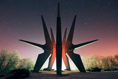 two large metal sculptures in the middle of a field at night with stars above them