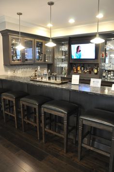 a bar with four stools in front of it and a television on the wall