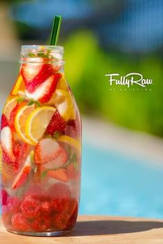 a mason jar filled with sliced fruit and lemons on top of a blue table