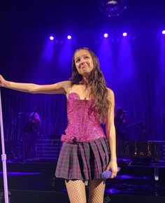 a woman standing on top of a stage holding a pole