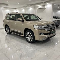 a tan toyota land cruiser is parked in a showroom with other cars behind it