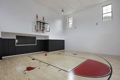 an empty basketball court in a gym with wooden flooring and black cabinets on the wall