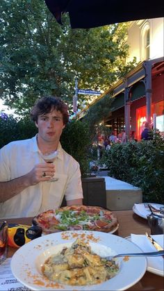 a man sitting at a table with a plate of food and drink in front of him