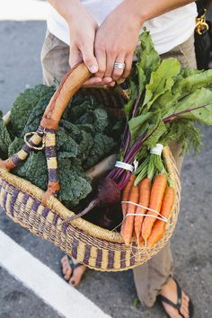 a person holding a basket full of vegetables