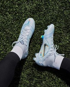 the feet of a person wearing blue and white shoes on green grass with black leggings