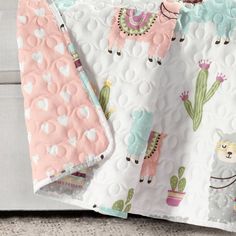 two baby blankets with llamas and cactus designs on them, one is pink