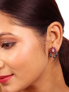 The Shanvi stud earring, meticulously crafted from 925 silver, features an intricately designed oval-shaped floral motif adorned with red kundan and white kundan stones. It is elegantly complemented by ball dangles. This Shanvi stud earring is a versatile piece suitable for daily wear and perfectly suited for any occasion. Please refer to the pictures of the jewelry worn on a model to get a clear idea of the size. Condition: New. This product is intricately designed and meticulously handcrafted with exceptional care by our skilled silversmiths, employing traditional Indian techniques. Every jewelry piece from Sashastrends bears a 925-hallmark stamp! Earring closure: Screw back. Material: 925 silver (Oxidized), red kundan, white kundan. Place of Origin: Bangalore, India. Fusion Style Bridal Earrings For Gift, Silver Pearl Earrings For Celebration, Traditional Silver Pearl Earrings For Formal Occasions, Silver Round Pearl Earrings For Celebration, Fusion Style Silver Pearl Earrings For Celebration, Silver Fusion Pearl Earrings For Celebration, Sterling Silver Fusion Bridal Earrings For Celebrations, Hallmarked Pearl Earrings For Festive Occasion, Festive Hallmarked Pearl Earrings