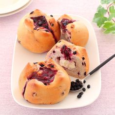 three blueberry muffins on a plate with a spoon